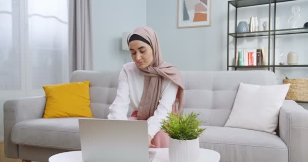 Midden plan van moslim zakenvrouw in hijab die werkt op laptop computer op het werk ruimte. Geconcentreerde dame aan het typen op het werk. Vrouw professioneel werken met documenten in het thuiskantoor. — Stockvideo