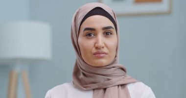 Profesyonel müslüman iş kadınının portresi. Ciddi bir yüz ifadesi olan kameraya bakıyor. Ofis arka planında geleneksel başörtüsü takıyor..