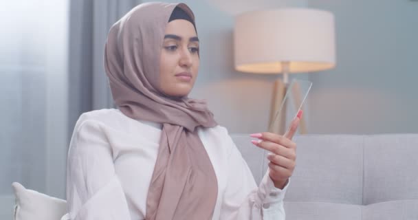 Close up retrato mulher muçulmana em hijab usando um tablet de vidro futurista com a mais recente tecnologia holográfica avançada em casa dentro de casa. Internet display móvel, telefone, conceito de inovação moderna . — Vídeo de Stock