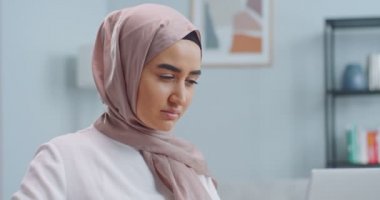 Genç ve güzel Müslüman kadın tesettürlü gözlük takıyor ve çalışmaya başlıyor. Öğrenci bilgisayarda gözlük kullanarak daktilo kullanıyor. Uzaktan çalışma, online öğrenim, ev ofis konsepti.