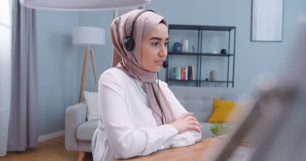 Mulher muçulmana feliz em hijab e fones de ouvido falando por webcam no treinamento webinar, olhando para laptop, menina estudante falando por videoconferência, professor de ensino on-line, consultoria conceito de cliente . — Vídeo de Stock