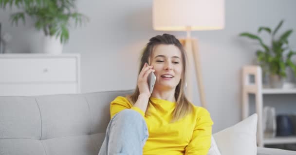 Lähikuva edessä muotokuva innoissaan kaunis tyttö puhuu matkapuhelimella kotona nauraa keskustella uutisia nauttia juoruja ystävien kanssa. Käsite ihmiset, viestintä ja talon käsite. — kuvapankkivideo