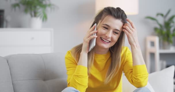 Portræt af pige i en gul sweater i hjemmekontoret, sidder og taler i telefon med sin forlovede, flirter med sin kæreste. Begrebet moderne liv, kommunikation, relationer, livsstil. – Stock-video
