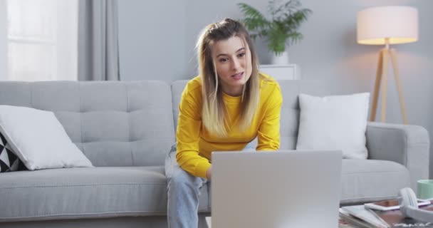 Femme d'affaires conduisant une vidéoconférence avec des collègues utilisant un ordinateur, expliquant le plan de travail en ligne pendant la quarantaine. Une femme travaille par liaison vidéo dans un cadre informel dans un bureau à domicile. — Video
