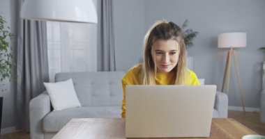 Kanepede oturup online mağazadan alışveriş yapan tatlı bir kız. Sanal danışman çevrimiçi mağazada ödeme yapmaya yardım ediyor. Telefonunu ve banka kartını kullanarak alışveriş yapan güzel bir kadın..