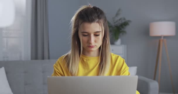 Chica feliz sentado en el sofá, el uso de la computadora en casa, escribiendo mensaje, charlando en línea en citas aplicación, comunicarse con amigos o de compras. El concepto de trabajo en línea en el hogar y el estilo de vida . — Vídeo de stock