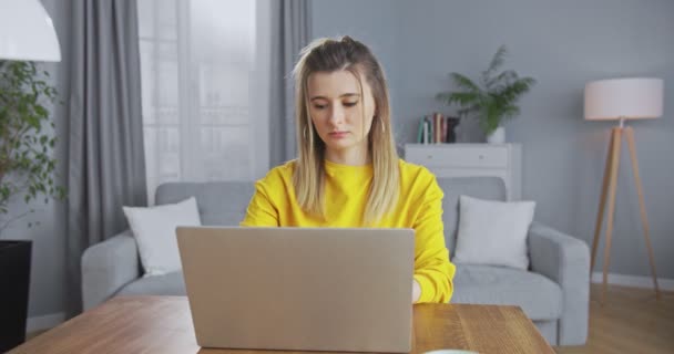 Smuk kvindelig freelancer efterbehandling arbejder med computer, lukker laptop og smiler lykkeligt til kameraet. Glædelig arbejdsdag. Arbejde hjemmefra, karantænearbejde, onlinetræningskoncept – Stock-video