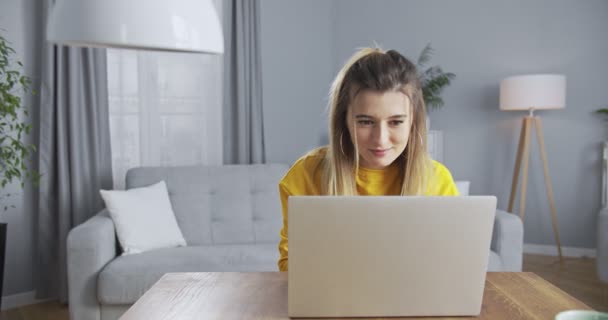 Leuk meisje op de bank die aankopen doet in een online winkel. Virtuele consultant helpt bij het verrichten van betalingen in de online winkel. Een mooie vrouw die betaald voor winkelen met haar telefoon en bankkaart. — Stockvideo