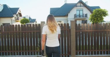 Tıbbi maske ve lastik eldiven takmış genç beyaz erkek kurye. Bisikletle müşteriye kese kağıdında yiyecek getiriyor. Güzel bir kadının kapıdan çıkıp siparişi alışı..