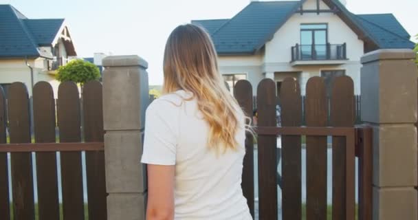 Beautiful young female in rubber gloves opening gate to pick up restaurant order. Hardworking delivery guy geting the food in paper bag out of backpack, giving to customer. Quarantine safety measures. — Stock Video