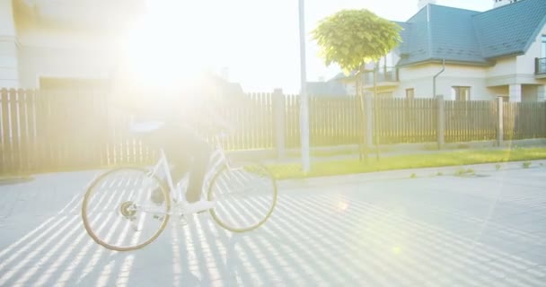 食品、食料品を配達する通りに自転車に乗って安全ヘルメットで陽気な白人男性宅配業者。魅力的な若いです配達男とともに熱バックパック探していますザ顧客ハウス. — ストック動画