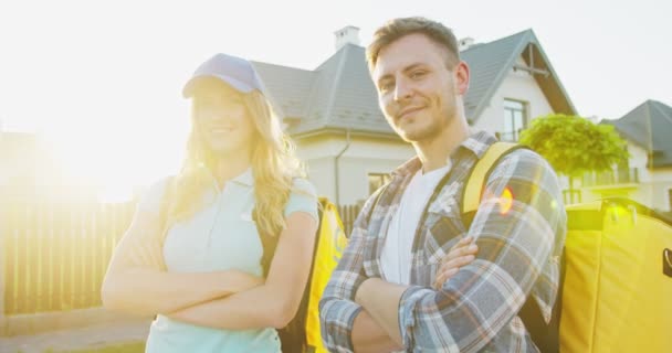 Портрет радостных мужчин и женщин-курьеров с рюкзаками. Happy delivery man and woman with cross hands looking and smiling at camera. Карантинный пандемический период, доставка еды. Оставайся дома.. — стоковое видео