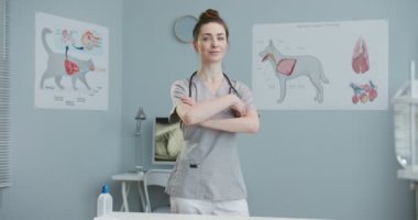 Kız laboratuvar çalışanı, ellerini göğsüne koyuyor. Steteskoplu veteriner doktor kameraya bakıyor. Evcil hayvan bakımı, veterinerlik, sağlıklı hayvanlar.