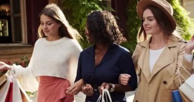 Şehirdeki farklı melez kadınların portresi. Alışveriş torbalarıyla güzel bir Afrikalı Amerikalı kız yürürken arkadaşlarıyla konuşuyor. Açık havada gülümseyen güzel beyaz kadınlar. Alıcı konsepti