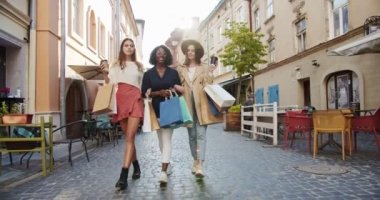 Açık havadan alışveriş yaptıktan sonra çok ırklı, güzel genç kadınlar. Güzel beyaz ve Afrikalı Amerikalı kızlar gün ışığında sokakta yürürken gülümsüyorlar. Şehirde boş zaman. Alışveriş konsepti