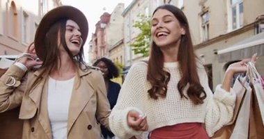 Güzel neşeli melez kadınlar gün ışığında sokakta yürüyorlar. Alışveriş yaptıktan sonra gülümseyen güzel kadınlar. Afro-Amerikalı ve beyaz kadınlar dışarıda gülüyor. Portre konsepti