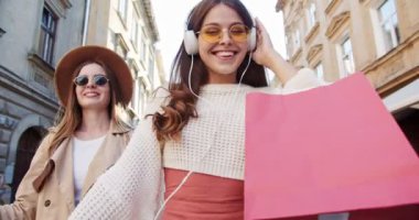 Çok ırklı güzel kızların açık havada keyifli yürüyüşlerinin yakın portresi. Beyaz bir kız sokakta kulaklıkla müzik dinliyor. Güneş gözlüklü neşeli Afrikalı Amerikalı gülümsüyor. Eğlenceli konsept