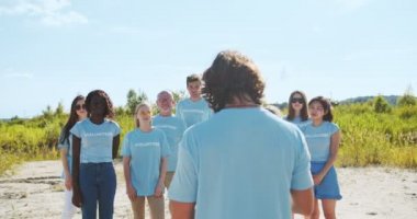 Gönüllü bir akıl hocası, çok ırklı insanları gönüllü faaliyetler hakkında planlayıp bilgilendiriyor. Bir grup gönüllü, liderleri dinliyor ve ellerini kaldırıyor. Ekoloji, kirlilik kavramı.