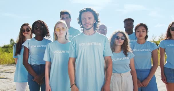 Eine multiethnische Gruppe von Freiwilligen rettet den Planeten Erde, sammelt Müll, Abfall. Aktive Umweltschützer stehen zusammen und schauen in die Kamera. Freiwilliges Engagement, globales Konzept. — Stockvideo