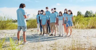 Gönüllü lider, gönüllü faaliyet talimatı veren ve planlayan bir pano ile. Akıl hocasını dinleyen ve el kaldıran bir grup aktivist. Doğa sorunları endişe ve çevre koruma.