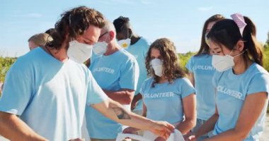 Çevresel koruma için gönüllü program. Maskeli aktivistlerin lideri çöpleri dağıtıyor, çöp torbalarını da plaj temizliği için. Gönüllü olmak, küresel sorun, çevreci aktivite kavramı.