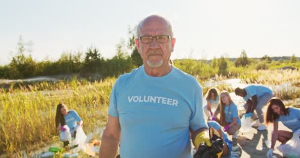 Un'organizzazione di volontariato che conserva l'ambiente per salvare il nostro pianeta. Un eco-attivista anziano che tiene un sacco della spazzatura con rifiuti e guarda la telecamera. Concetto di conservazione ambientale. — Video Stock