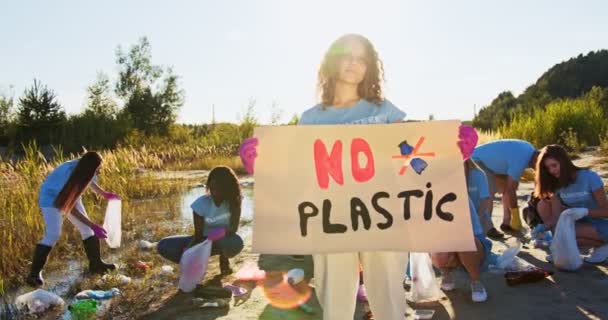 Mladý teenager, který chrání životní prostředí, chrání přírodu. Žena teenager dobrovolník drží plakát s No Plastic, protestuje proti plastové využití. Eko-freindly society concept. — Stock video