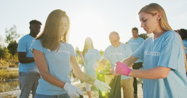 Hermosas jóvenes mujeres activistas caucásicas conservando el medio ambiente. Mujeres eco voluntarias presionando botellas y tirando, poniendo en una basura, bolsa de basura para reciclar. Concepto de preservación. — Vídeos de Stock