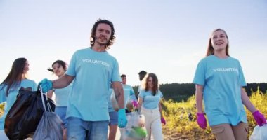 Bir grup etnik çeşitlilikte gönüllü çöp poşetlerinden sonra çöp toplayarak yürüyor. Mutlu ve yorgun aktivistler konuşuyor, çak bir beşlik. Arkadaşlık, gönüllülük, takım çalışması konsepti..