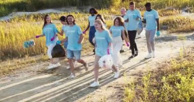 Çöp poşetlerinden sonra çöp toplayan mutlu gönüllüler. Çok ırklı çevreciler işten sonra seviniyor, beşlik çakıyor ve konuşuyorlar. Arkadaşlık, takım ruhu, gönüllülük konsepti..