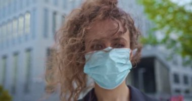 Resmi bir takım elbise ve tıbbi maske takmış çekici kıvırcık saçlı, beyaz bir aygır. Yetişkin kadın işçiler kameraya bakıp antiseptik ve dezenfektan sıkarlar. Sağlık, ilaç, virüs.