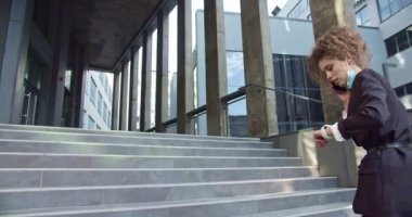 Aceleci kadın finans işçisi işe geç kalıyor. Kafkasyalı genç iş kadını aceleyle ofise gidiyor, telefonla konuşuyor ve saati kontrol ediyor. Meslek, istihdam kavramı.