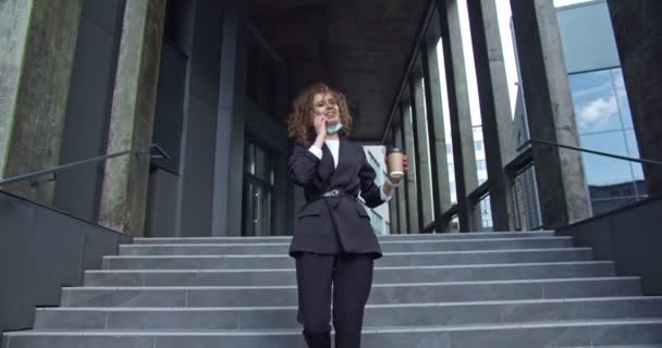 Attraente donna d'affari adulta che indossa un abito formale con una tazza di caffè durante una pausa all'aperto. Lavoratrice sorridente che parla al telefono e controlla un orologio del tempo. Giorni lavorativi. — Video Stock