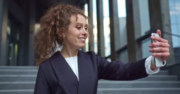 Cheerful Caucasian businesswoman in a formal suit speaking on job hiring. Young office worker talking with her friend, family via a video chat outdoors. Recruitment, social media, communication. — Stock Video