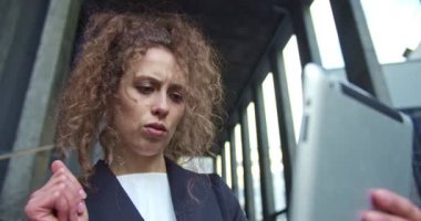 Şirket binasının dışında takım elbiseli çekici genç bir ofis çalışanı. Kafkasyalı iş kadını tabletteki bir görüntülü konuşma üzerinden arkadaşıyla konuşuyor. İletişim, İnternet.