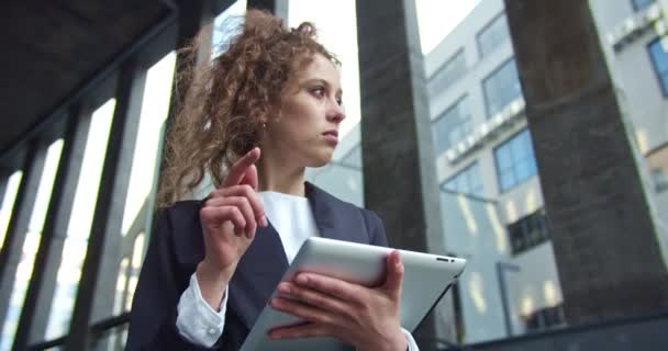 Smart office manager draagt een formeel pak in de zakenwijk. Goed uitziende blanke zakenvrouw scrollen de nieuwsfeed en typen op de tablet. Digitalisering, social media concept. — Stockvideo