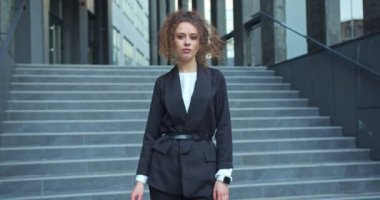 Şirket binasının önünde duran resmi takım elbiseli çekici, kendine güvenen bir iş kadını. Akıllı beyaz kadın ofis çalışanı. Arkasına saklanıp kameraya bakıyor. İş, adam toplama..