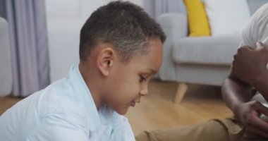 Kapalı bir odada yerde oturmuş babasıyla oynayan mutlu, küçük Afrikalı Amerikalı çocuğu yakından çek. Neşeli küçük çocuk evde uçak oyuncağıyla oynarken babasıyla eğleniyor. Çocukluk kavramı
