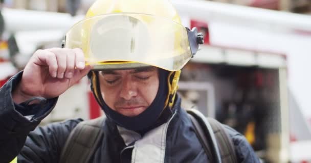 Gros plan portrait d'un pompier dans un casque et un équipement de goéland debout à côté de la voiture. Casque d'ouverture de sauveteur et sourire en regardant la caméra. Concept de sauver des vies, profession héroïque, sécurité incendie — Video