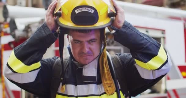 Gros plan portrait d'un pompier dans un casque et un équipement de goéland debout à côté de la voiture. Sauveteur enlève le casque et sourit en regardant la caméra. Concept de sauver des vies, profession héroïque, sécurité incendie — Video