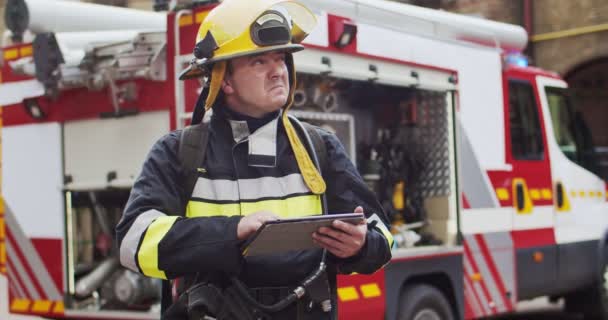 Portrét hasiče v helmě a vybavení racka zobrazující po stranách a zapisující data do tabletu. Záchranář pracující s nejnovějšími technologiemi. Koncept záchrany životů, hrdinské profese, požární bezpečnosti — Stock video