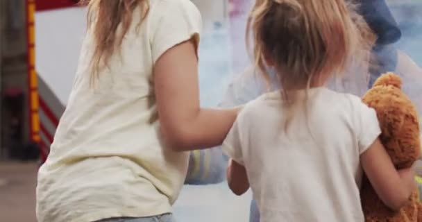 Portrait of injured little girls sisters reunites with their loving father fireman in helmet and gull equipment. Smoke from fire covers rescuers and car. Firefighter looking at camera. — Stock Video