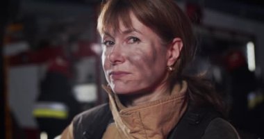 Akşamları kameraya bakan Kafkas bwomrunette kadın itfaiyecisinin portresini yakından çek. Hayat kurtarma kavramı, kahramanlık mesleği, yangın güvenliği.