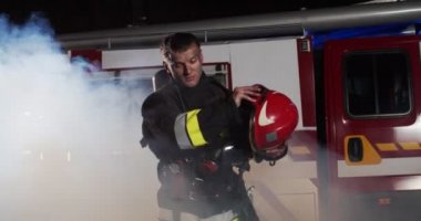 Kafkasyalı genç itfaiyecinin kaskını çıkarıp kırmızı kamyona doğru yürüyüp kameraya bakmasından oluşan bir plan. Hayat kurtarma, kahramanlık mesleği, yangın güvenliği kavramı.