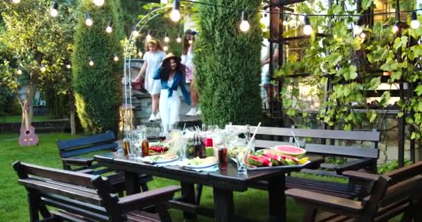 Jóvenes multiétnicos felices reunidos en el jardín. Caucásico guapos chicos y hermosas chicas teniendo fiesta al aire libre. Asiática alegre chica sonriendo y abrazando a un amigo. Concepto divertido — Vídeos de Stock