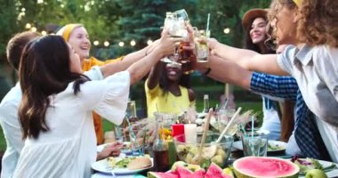 Çok ırklı mutlu gençler dışarıda toplandı. Erkek ve dişi neşeli arkadaşlar bahçede yemek yiyip içiyorlar. Gençliğin keyfi yerinde kadehleri kaldırıyor ve şıngırdıyor. Yaz partisi konsepti