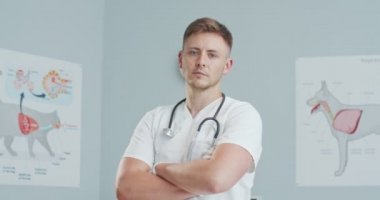 Genç ve güzel erkek veteriner ofiste kollarını kavuşturuyor. Veteriner hastanesinde steteskopla gülümseyen doktor. Hayvan bakımı, veterinerlik, sağlıklı hayvanlar..