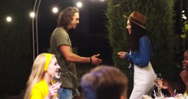 Çok ırklı gençler dışarıda eğleniyor. Yaz akşamında mutlu beyaz adam ve kadın dansları. Masada otururken gülümseyen ve sohbet eden Afrikalı Amerikalı ve Asyalı kızlar. Parti konsepti