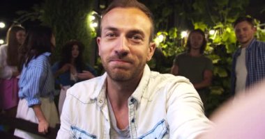 Dışarıdaki videoda konuşan yakışıklı beyaz bir adam. Güzel, mutlu, Afro-Amerikan ve Asyalı kızlar gülümsüyor. Neşeli adamların keyfi yerinde. Akşamki bahçe partisinde çok ırklı arkadaşlar el sallıyor.