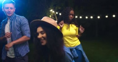 Partide bahçede dans eden güzel melez kızları yakından çek. Kafkas ve Afrikalı Amerikalı neşeli kadınlar eğleniyor. Müziğe yönelen mutlu yakışıklı adam. Yaz akşamı bir araya geldik.